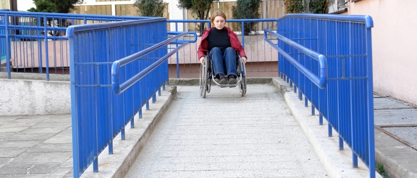 Fotografía de una mujer en silla de ruedas descendiendo por una rampa