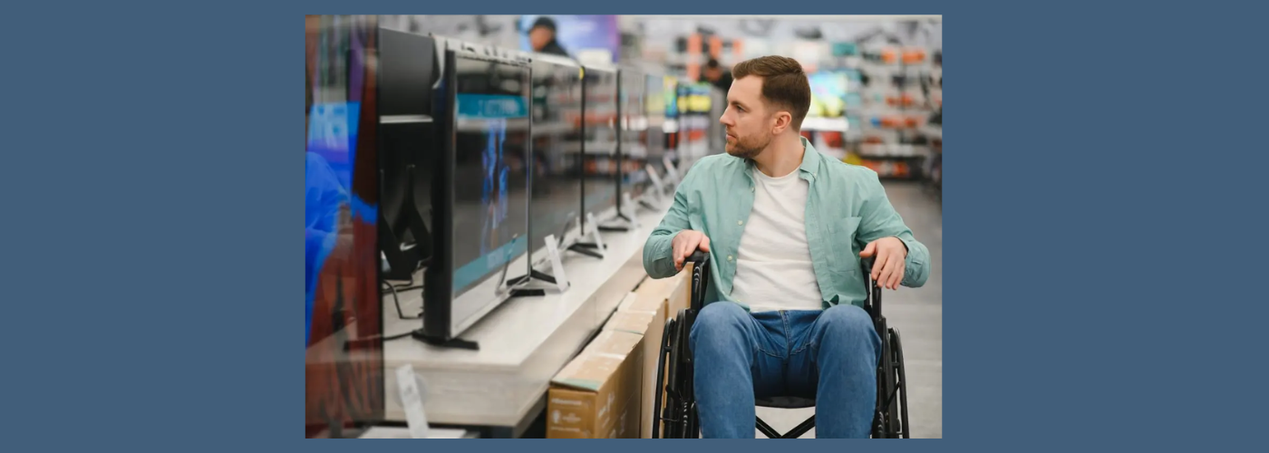 CERMI- Un joven en silla de ruedas observa televisores en un comercio